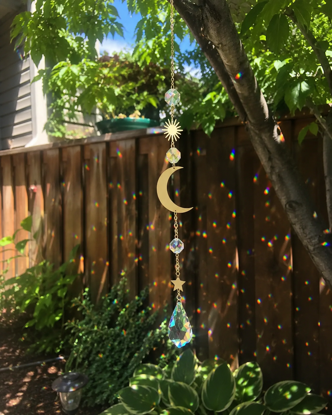Crystal moon suncatcher creating colorful rainbow reflections outdoors