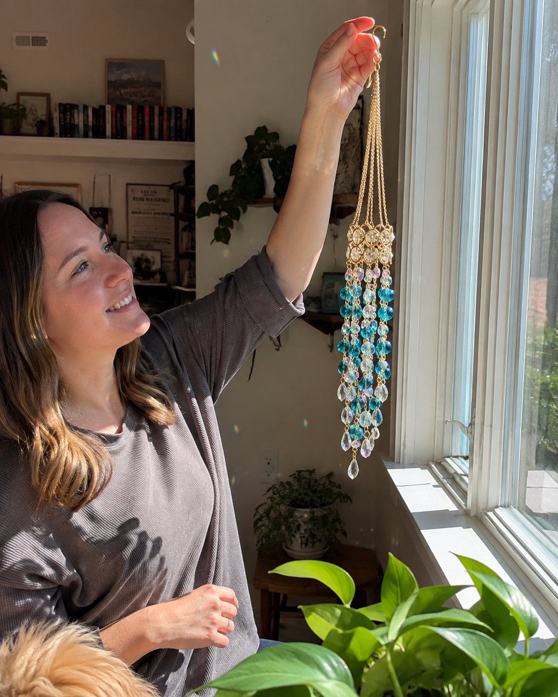 Woman holding crystal flower suncatcher beside a sunny window