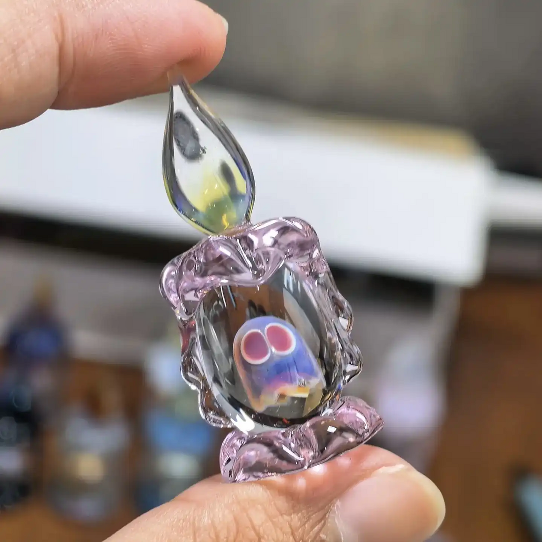 Pink ghost candle miniature glass figurine held between fingers